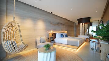 A modern hotel room with a large bed, a hanging chair, a round coffee table, and a large plant.