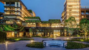 Ein modernes Hotel mit mehreren Etagen, Außenbereich und einem begrünten Innenhof.