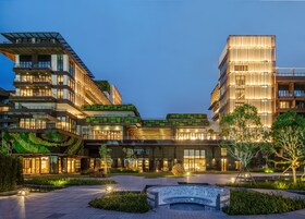 A modern hotel with multiple floors, outdoor seating, and a landscaped courtyard.