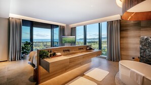 Ein modernes Badezimmer mit einer großzügigen Badewanne, einem hölzernen Waschtisch und einem großen Fenster mit schöner Aussicht.
