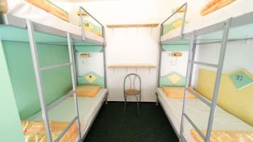 Un dormitorio con literas, tres literas, una silla y un estante.