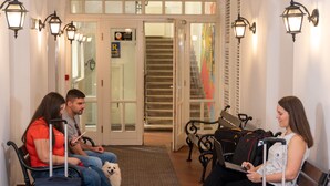 A waiting area with benches and a dog, a staircase, and a door with a sign. - MP Hostel Budapest (Budapest)