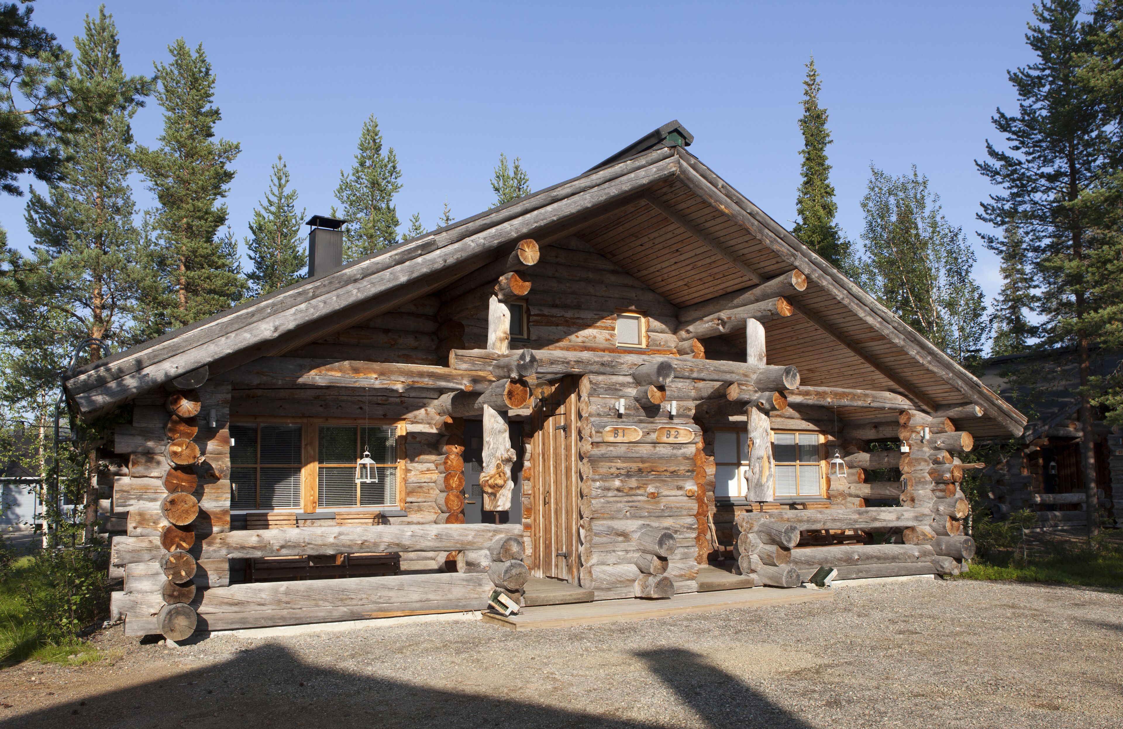 A log cabin with a steeply pitched roof, large windows, and a chimney.