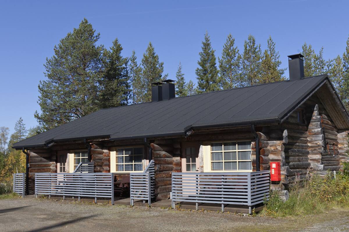 A log cabin with a sloped roof, large windows, and a chimney.