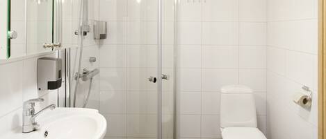 Un baño moderno con cabina de ducha de vidrio, un lavabo blanco y un inodoro.