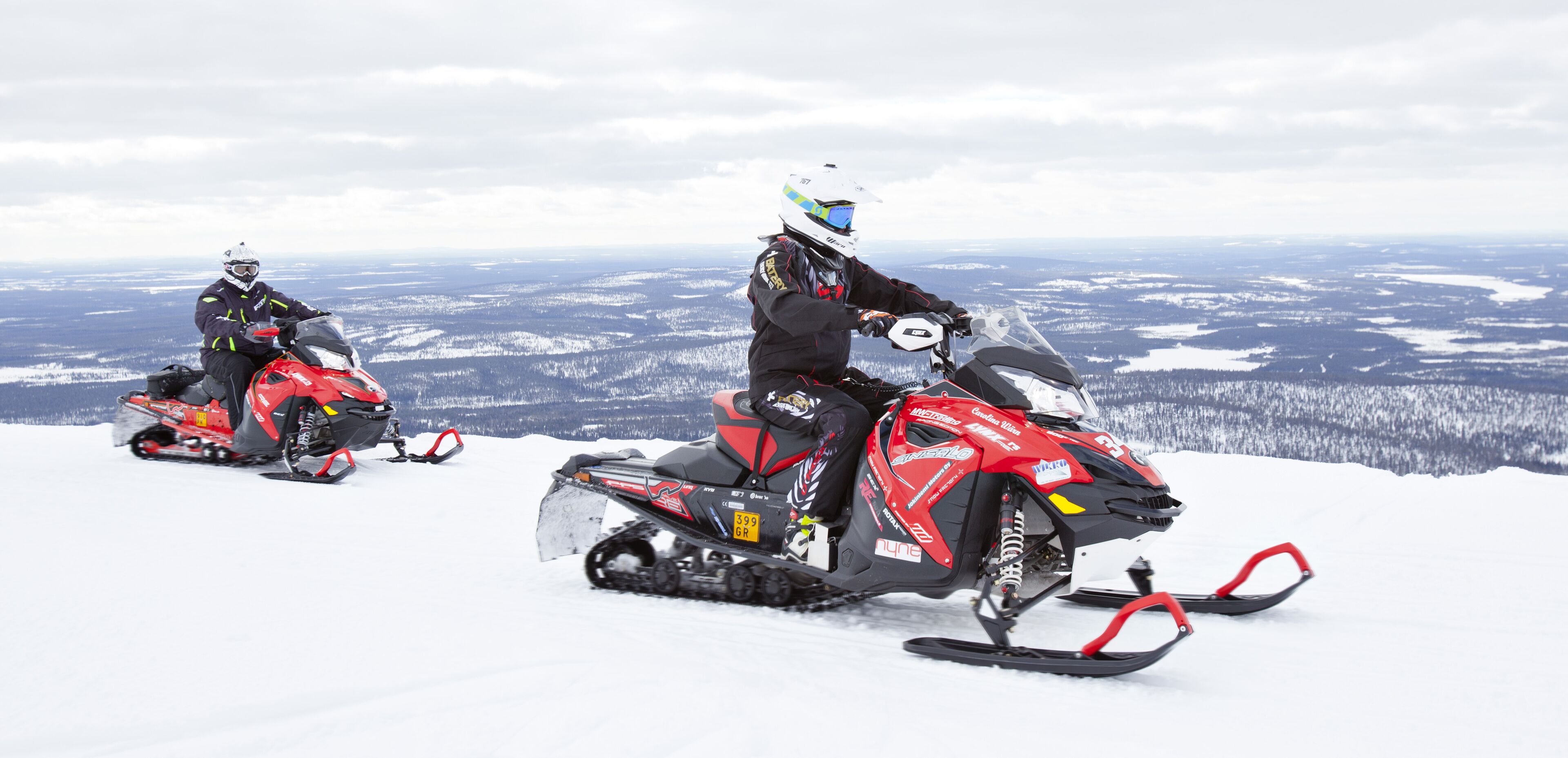 Dos motos de neu sobre un paisatge nevós amb una extensa vista del terreny.