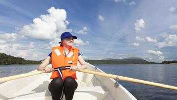 A person in a boat wearing an orange life jacket, holding a paddle.