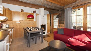 Un interior de cabaña acogedor con comedor, un sofá rojo y una chimenea.