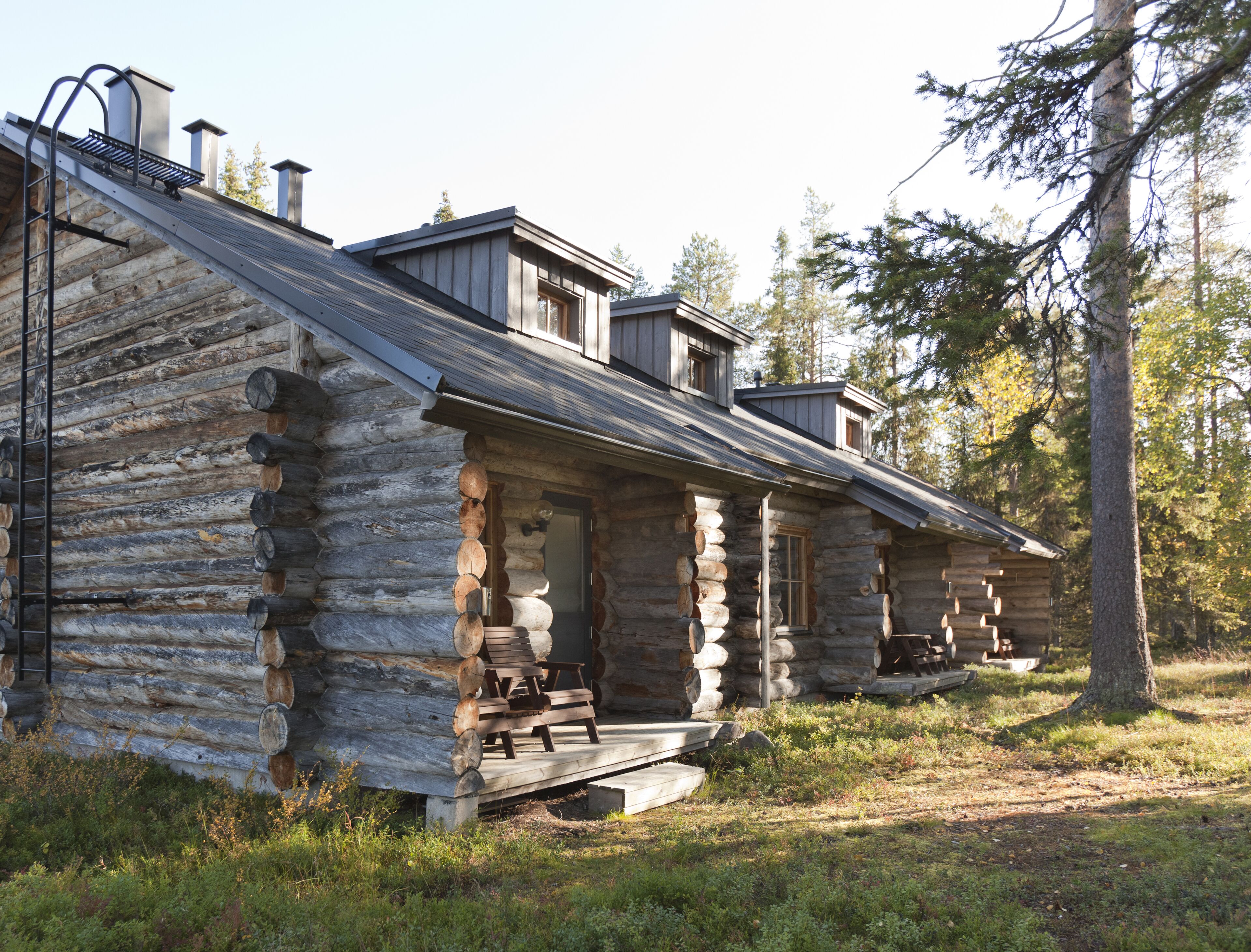 A log cabin with a porch, a chimney, and a small deck.