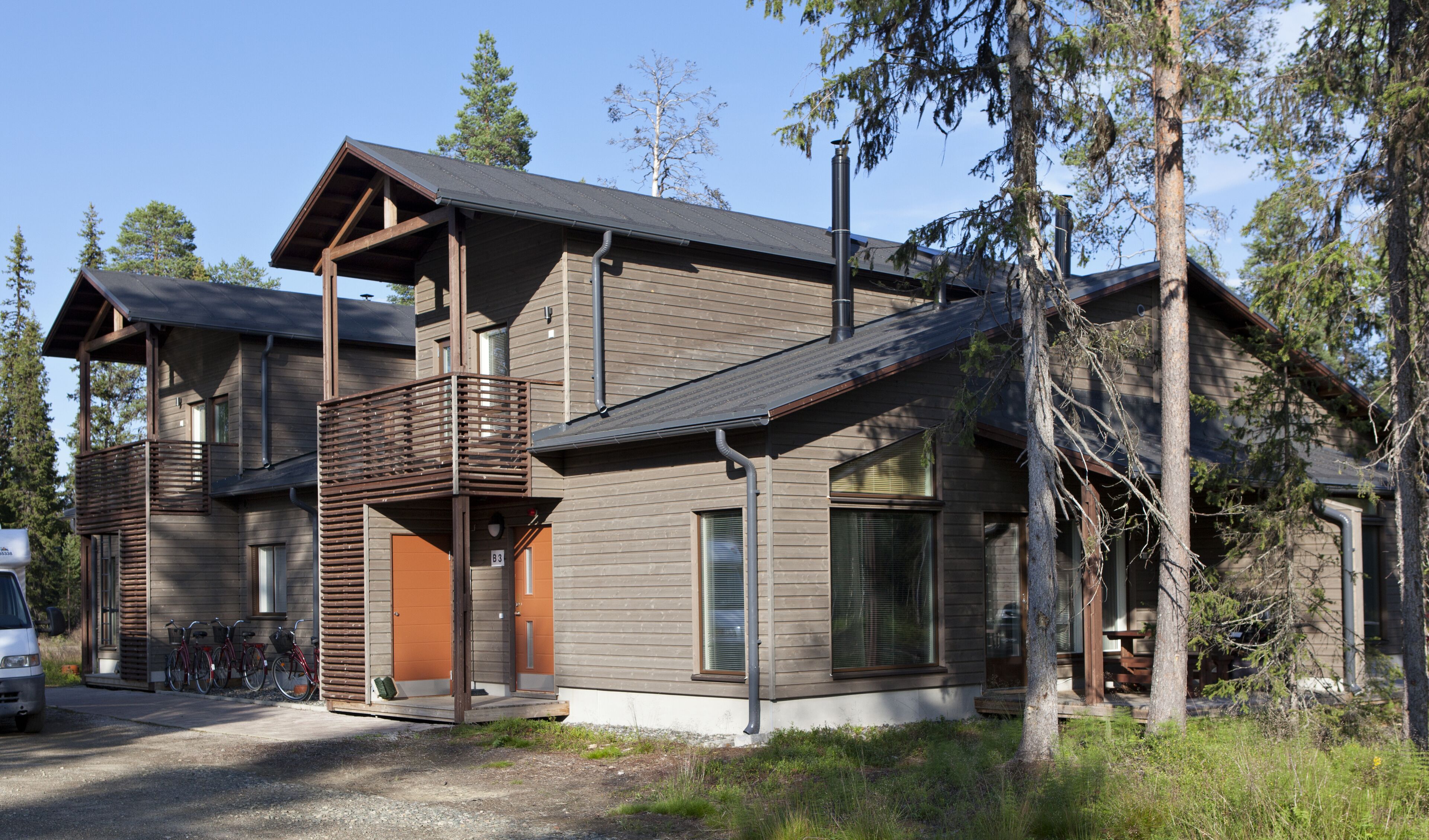 A modern two-story house with a balcony, large windows, and a garage.