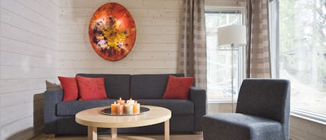 A modern living room with a grey sofa, a round coffee table with candles, and a grey armchair.