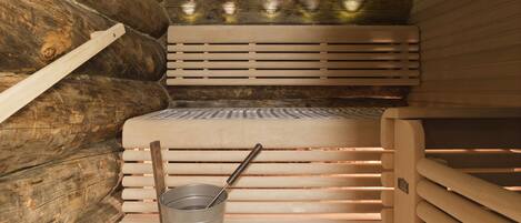 Un sauna avec des bancs en bois et un seau en métal.