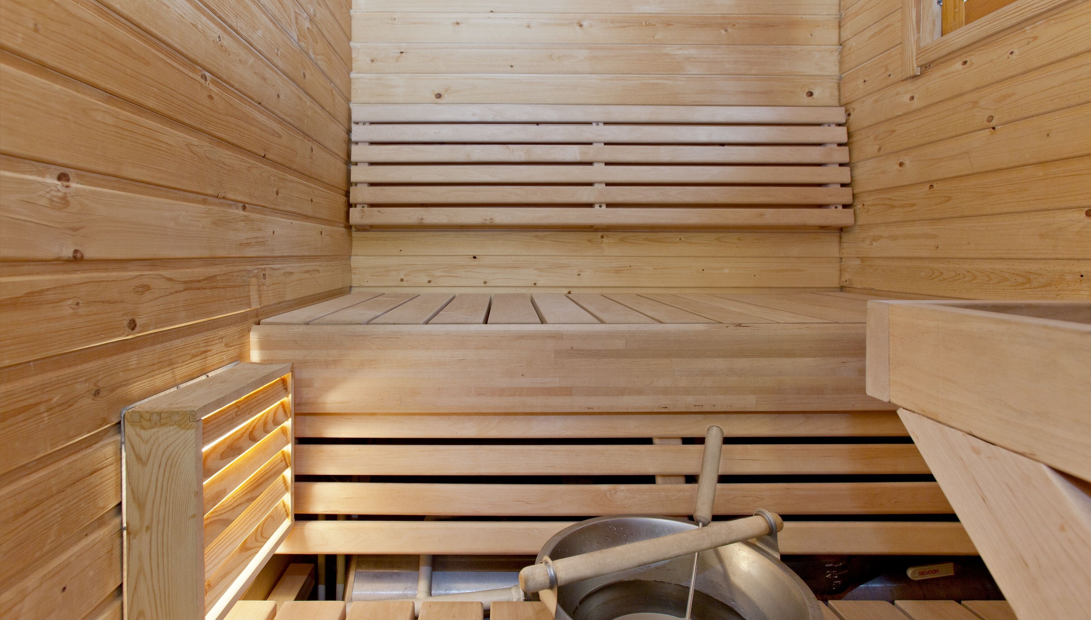 Eine Sauna mit Holzbänken und einem sichtbaren Heizsystem.