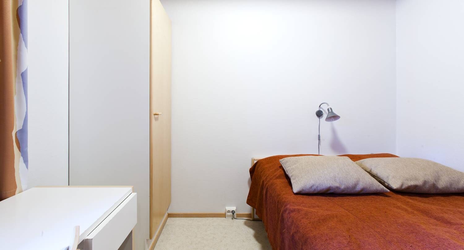 Una camera da letto con un letto, una lampada da comodino e un comò bianco.