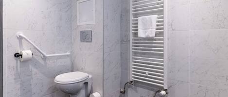 A modern bathroom with a toilet, grab bars, a towel rack, and a shower area.