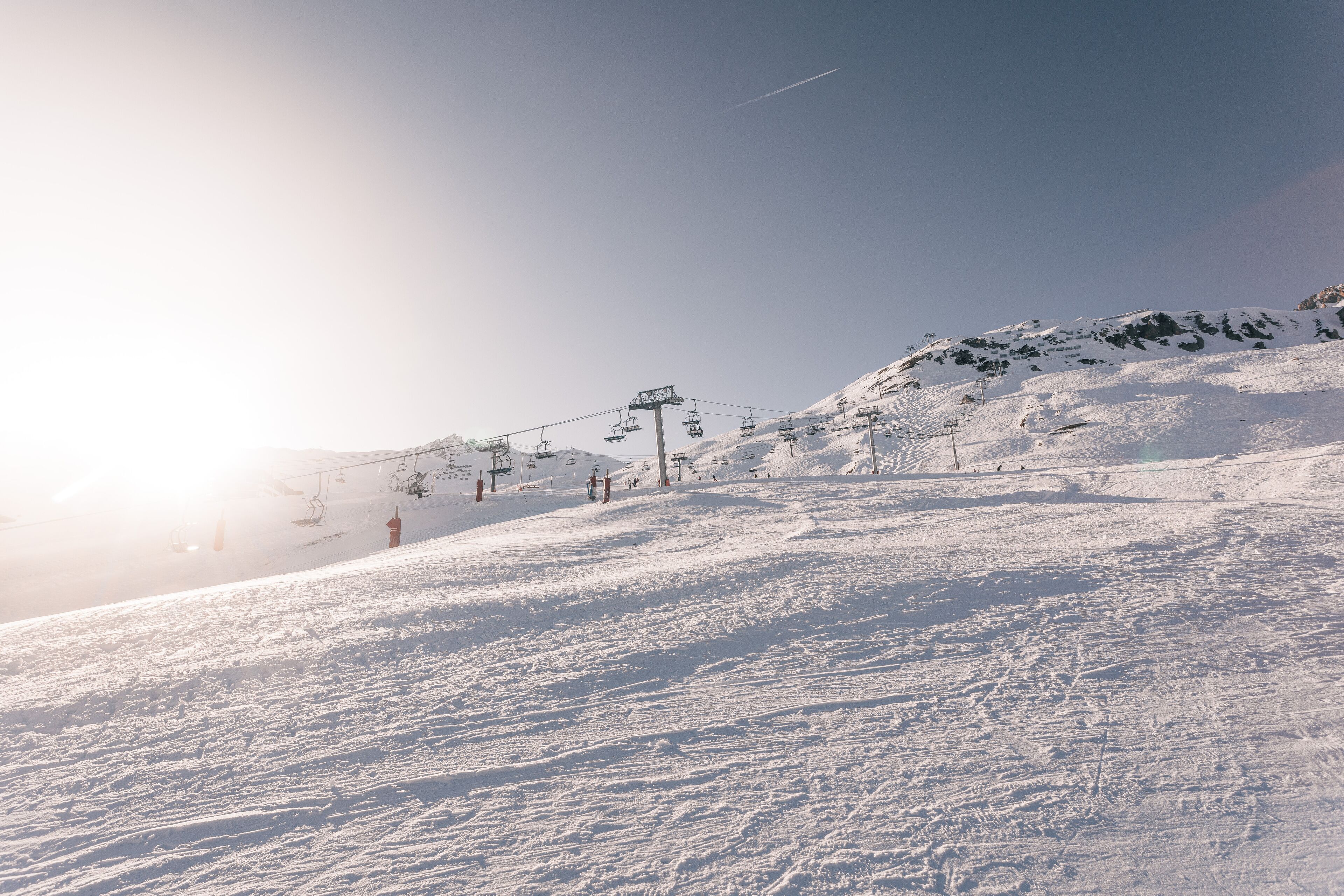 Een besneeuwde helling met skiliften en een heldere lucht.