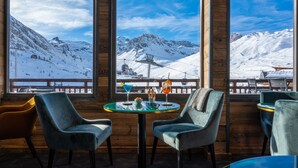 A cozy interior with large windows offering a view of a snowy mountain landscape. - Hôtel Le Levanna by Les Etincelles (Tignes)