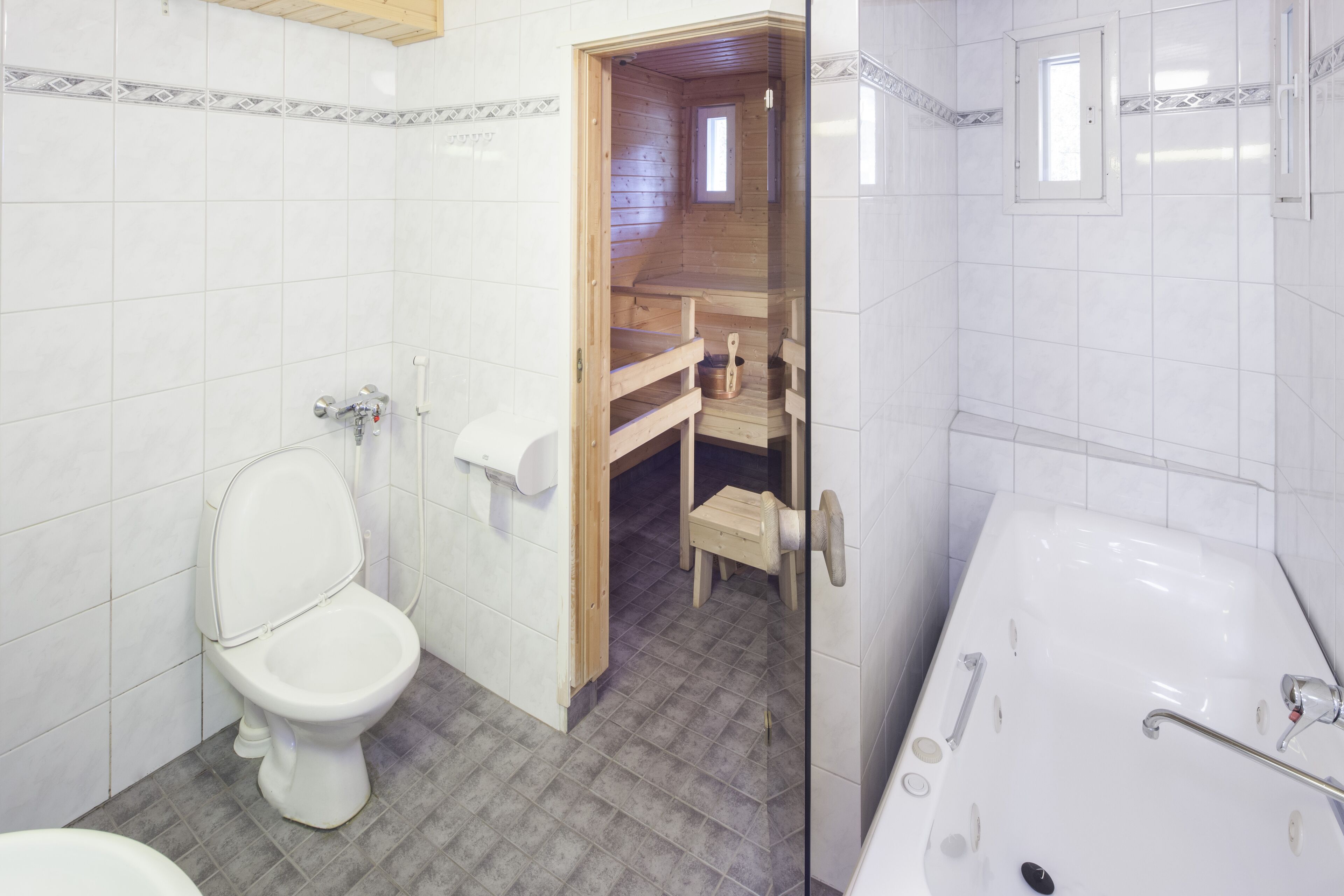 Een badkamer met toilet, badkuip en een douchecabine van hout.