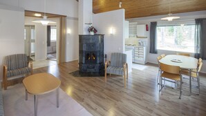 A spacious living area with a fireplace, wooden flooring, and a dining table with chairs. - Holiday Club Punkaharju (Savonlinna)