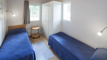 Un dormitorio con dos camas individuales, una mesita de noche pequeña, una ventana con cortinas e iluminación en el techo.