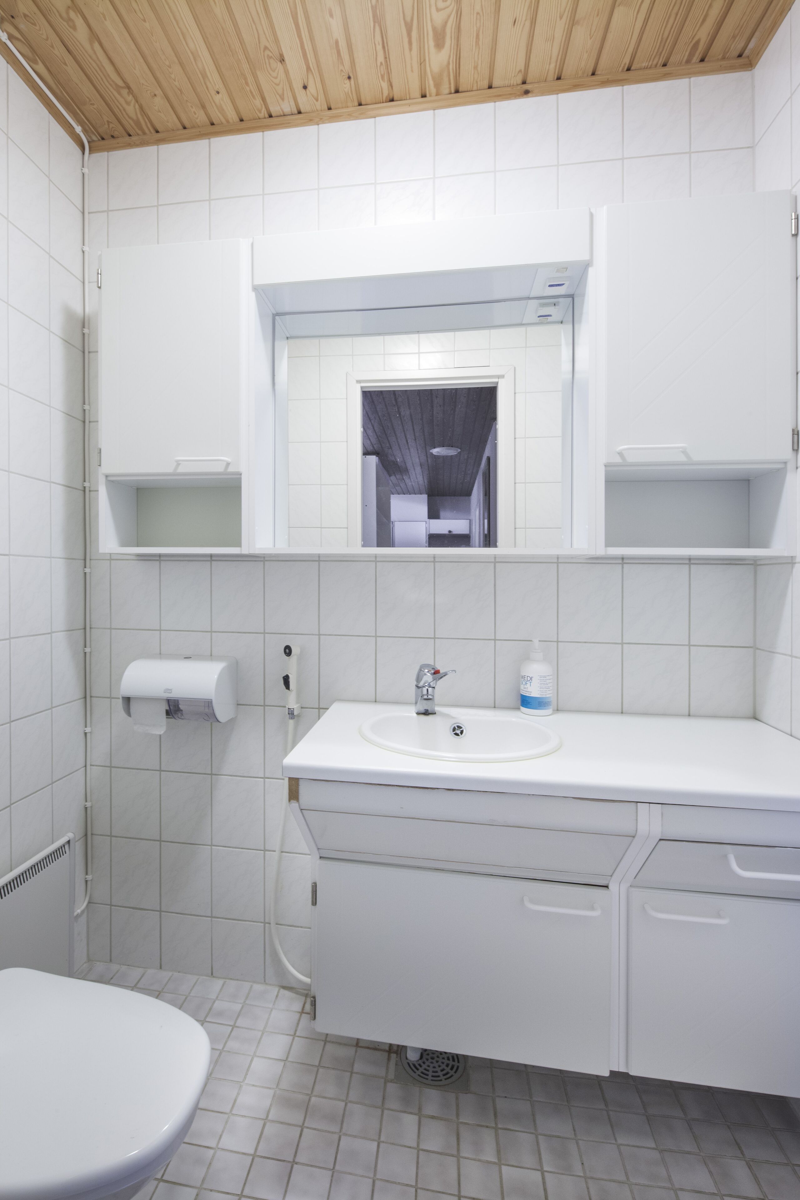 A modern bathroom with white fixtures, a toilet, a sink, and a mirror above the sink.