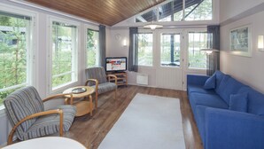 A spacious living room with a blue sofa, striped armchair, and a small table. - Holiday Club Punkaharju (Savonlinna)