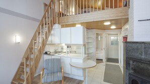 A modern kitchen with white cabinets, a wooden staircase, and a small dining area with a table and chair. - Holiday Club Punkaharju (Savonlinna)