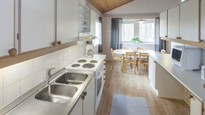 A modern kitchen with stainless steel appliances, a dining area with a table and chairs, and a view of the outdoors through a window. - Holiday Club Punkaharju (Savonlinna)