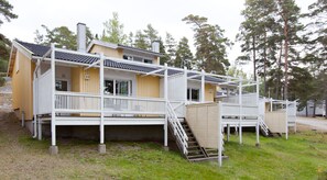 A two-story cabin with a balcony, a staircase, and a small deck area. - Holiday Club Airisto (Pargas)