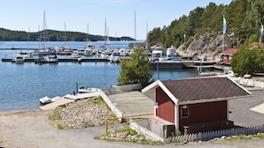 A marina with boats docked, a small wooden building, and a dock with a white picket fence. - Holiday Club Airisto (Pargas)