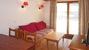 A cozy room with a wooden sofa, a wooden table, and two wall-mounted lamps. - Les Orres 1800: apt for 6, heated pool, sauna, ski-in/ski-out (Les Orres)