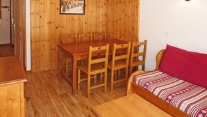 A wooden dining area with a table and chairs, a red lamp, and a patterned sofa. - Les Orres 1800: apt for 6, heated pool, sauna, ski-in/ski-out (Les Orres)