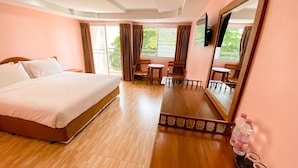 A hotel room with a large bed, a wooden dining table, two chairs, a small table, and a TV mounted on the wall. - A.A. Pattaya Golden Beach Hotel (Pattaya)