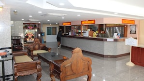 A reception area with a reception desk, a cashier, and a reception counter. There are wooden chairs and a table in the foreground. - A.A. Pattaya Golden Beach Hotel (Pattaya)