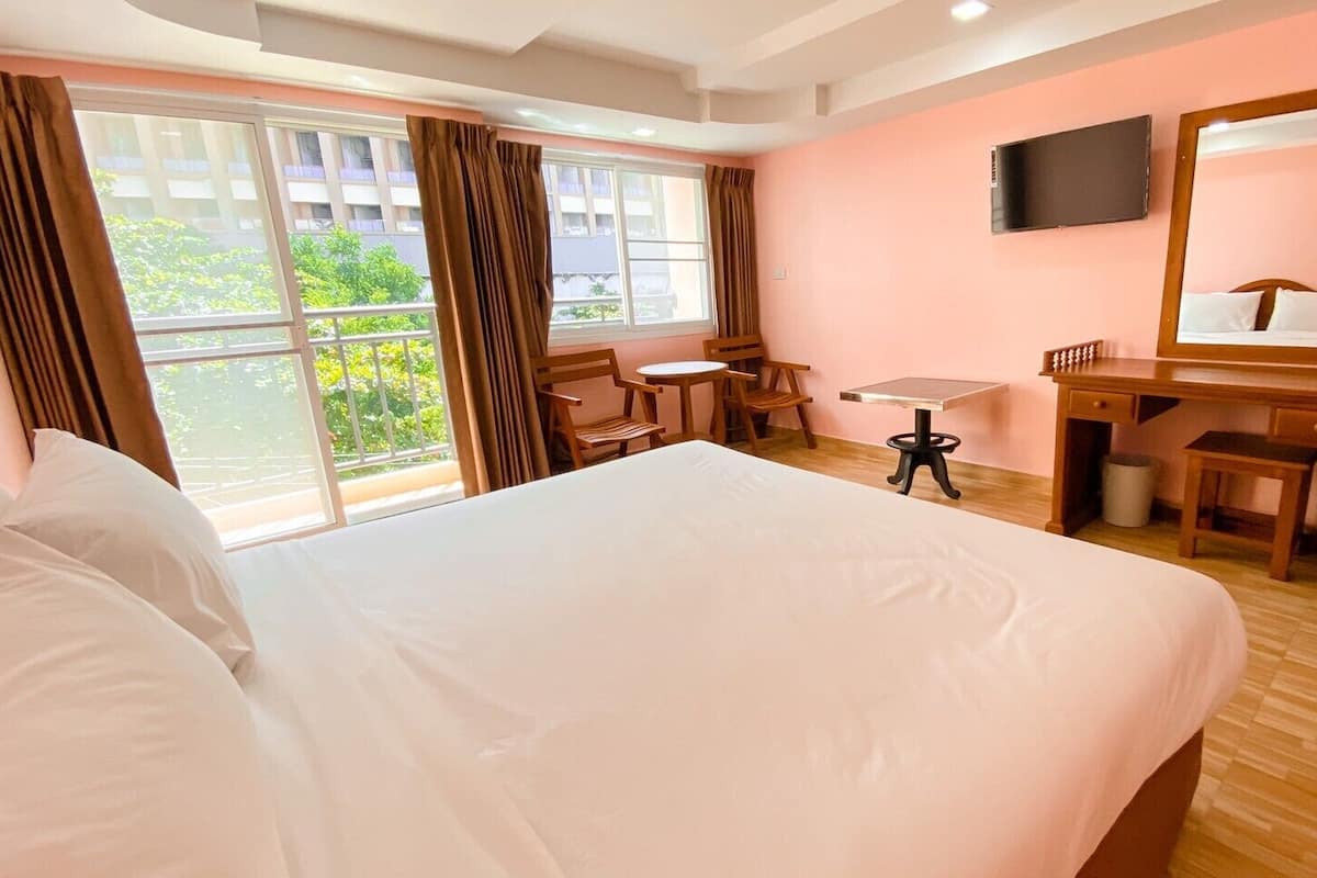 Hotelkamer met een groot bed, een bureau, een stoel, een klein tafeltje, een spiegel en een televisie.