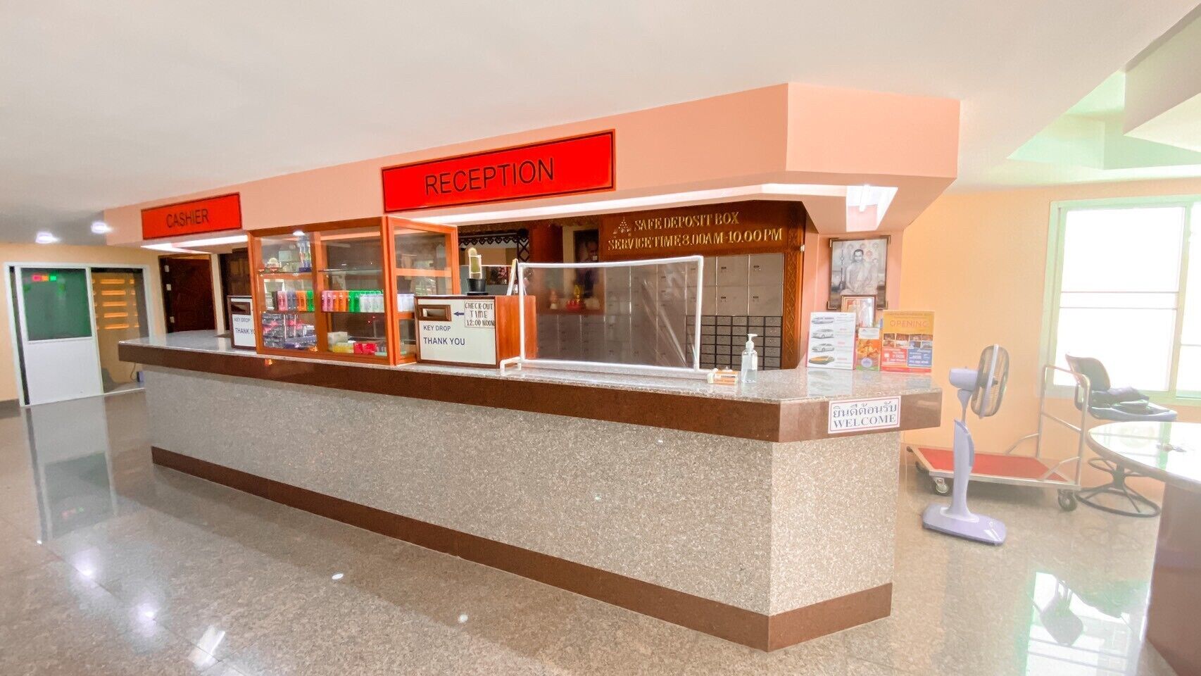A reception desk with a 'RECEPTION' sign, a 'CASHIER' sign, a 'SAFE DEPOSIT BOX' with service times, and a 'WELCOME' sign.