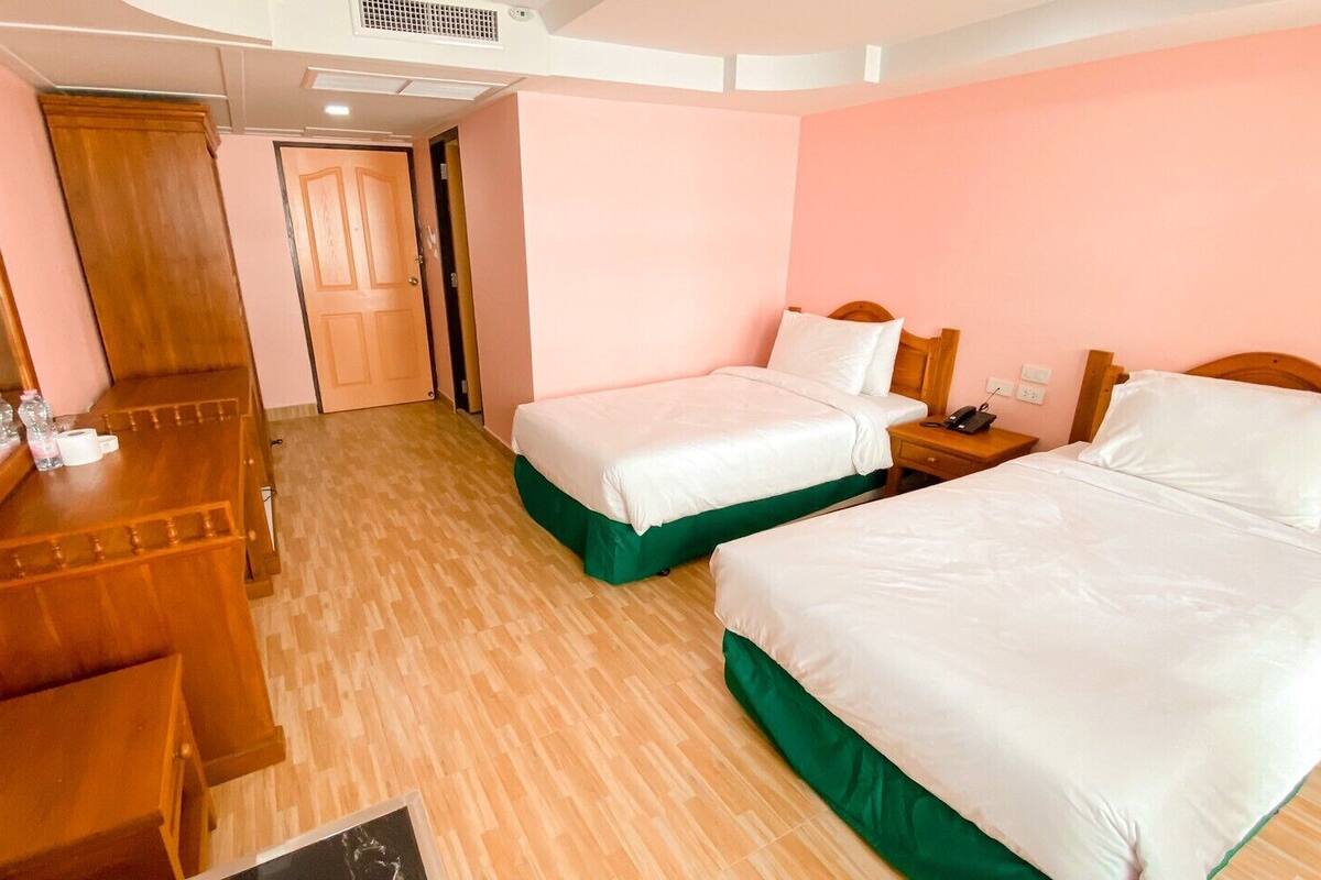 Een hotelkamer met twee bedden, een houten bureau, een spiegel en een deur.