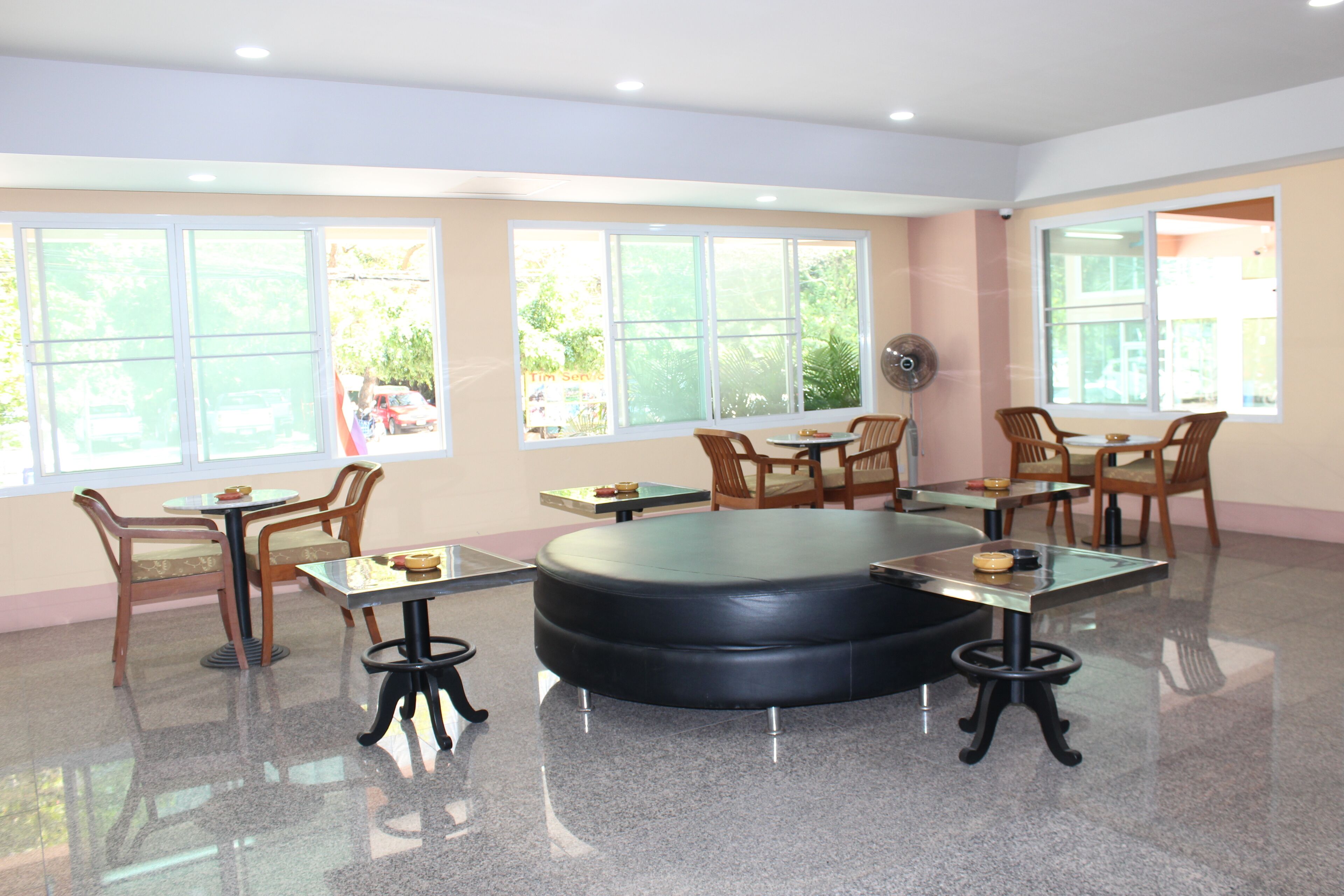 A spacious room with large windows, a round black table, and several wooden chairs.