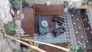 Un pequeño espacio exterior con mesa, cojines y una cesta tejida.