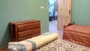 Un dormitorio con cama, cómoda de madera y alfombra estampada.