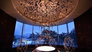 A modern interior with a round table, two hanging chairs, and a ceiling with geometric patterns. - Urabandai Lakeresort Nekomarikyu (Kitashiobara)