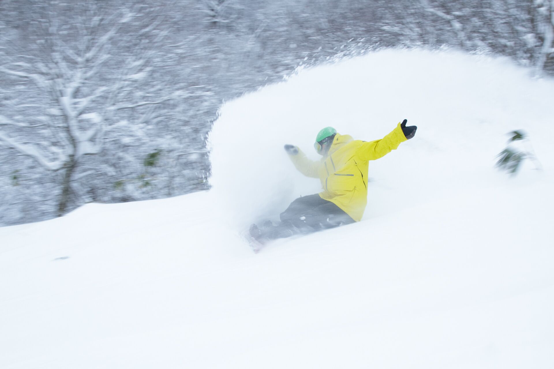 Uma pessoa com jaqueta amarela praticando snowboard em uma encosta coberta de neve.