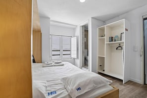 A hotel room with a bed, a wardrobe, and a bathroom visible through an open door. - Bica Ropers Suite, Studio apartment in the heart of the city (Lisbon)