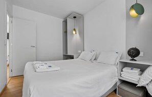 A modern bedroom with a bed, bedside tables, a globe, and a hanging light fixture.
