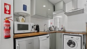 Eine kompakte Küche mit Mikrowelle, Kaffeemaschine, Geschirrspüler und Waschmaschine.