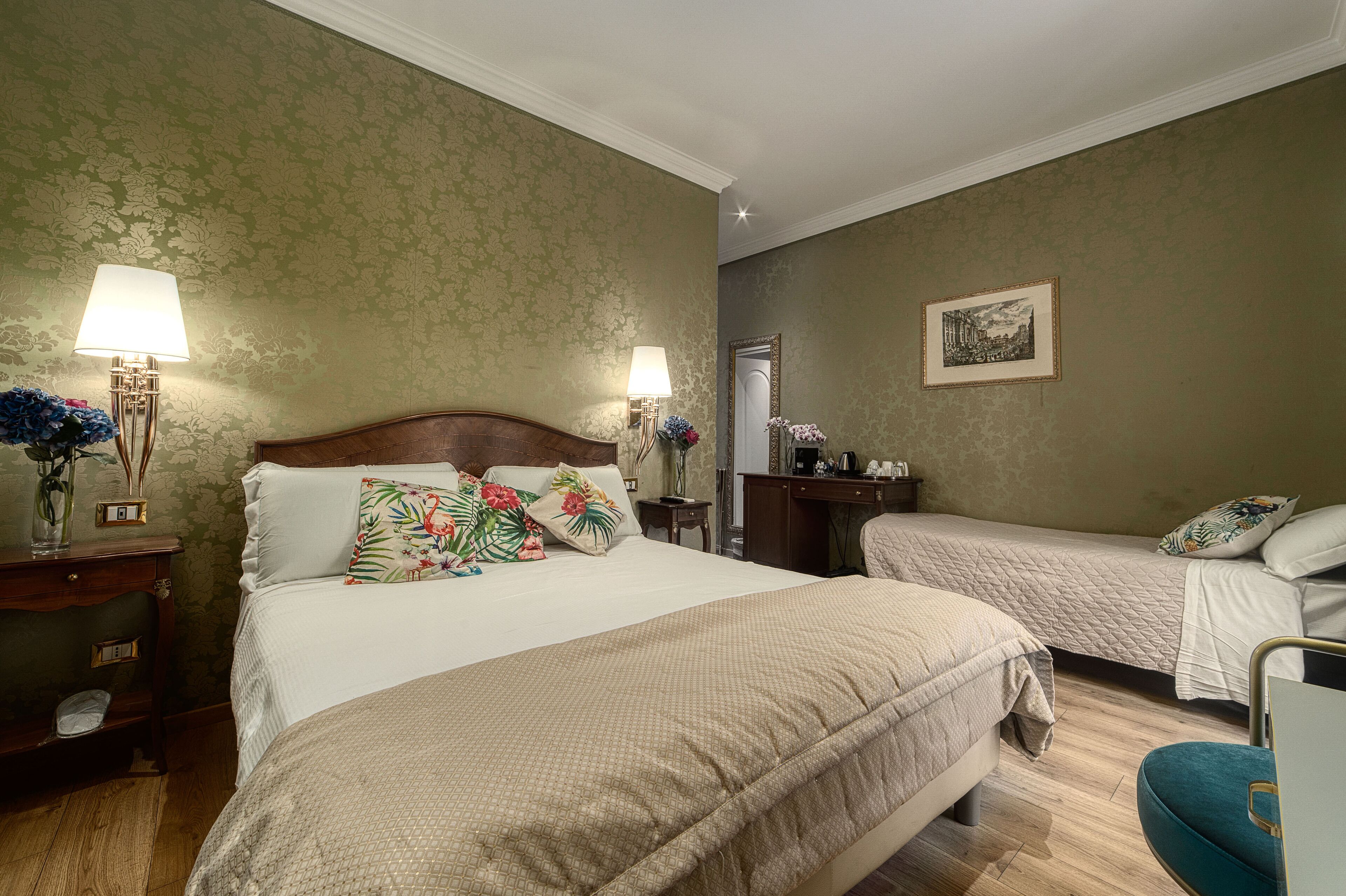 A hotel room with two beds, a desk, a chair, and a mirror.