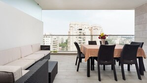 Un balcon avec un canapé et une table à manger, offrant une vue sur le paysage urbain.