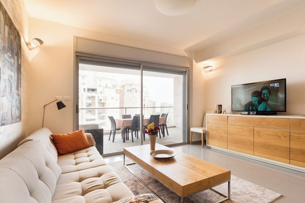 A modern living room with a sofa, coffee table, and a television on a wooden cabinet.