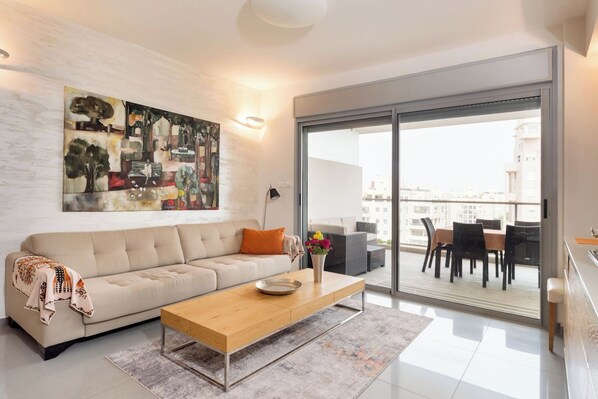 A modern living room with a sofa, coffee table, and a large abstract painting.