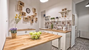 A kitchen with wooden countertops, white cabinets, and a tiled backsplash. There are wooden shelves with decorative items and a clock on the wall. - Budapest Passage 1 (Budapest)